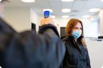 An image representing Voilà by Sobeys delivery teammate gets their temperature checked by a colleague.