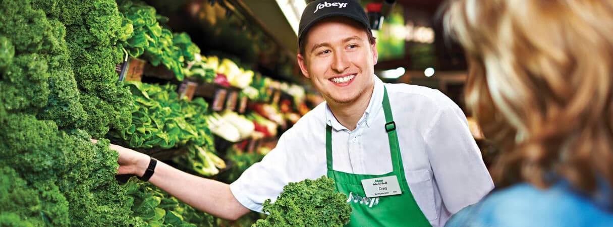 An image of a Sobeys teammate assisting his customer in buying fresh vegetables.